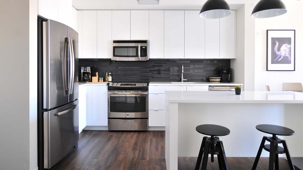 A bright, modern kitchen with a refrigerator, oven, dishwasher and microwave